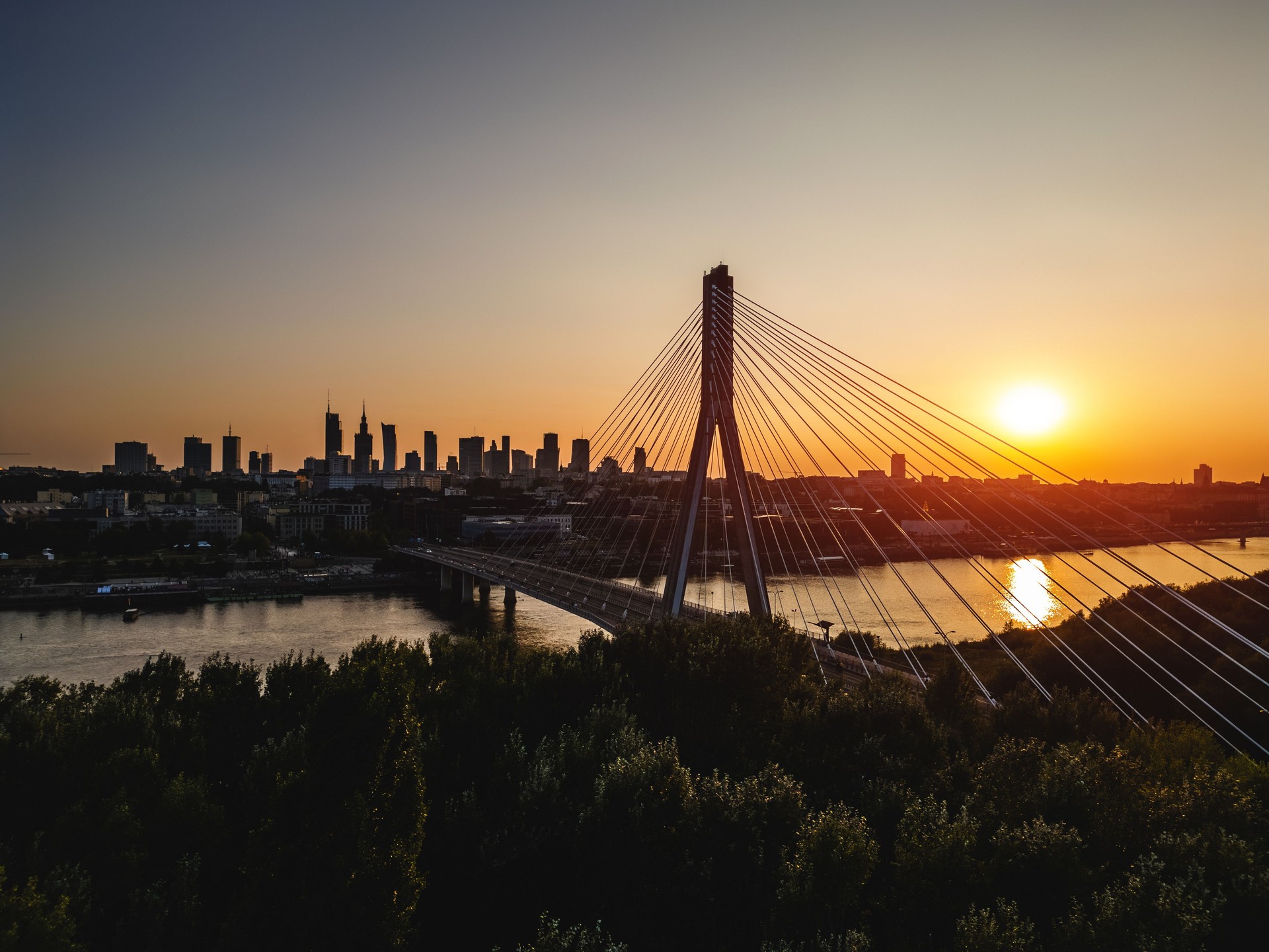 skyline of Warsaw city with downtown financial district and modern cable bridge over Vistula river at sunset, modern skyscrapers at background, aerial top view
