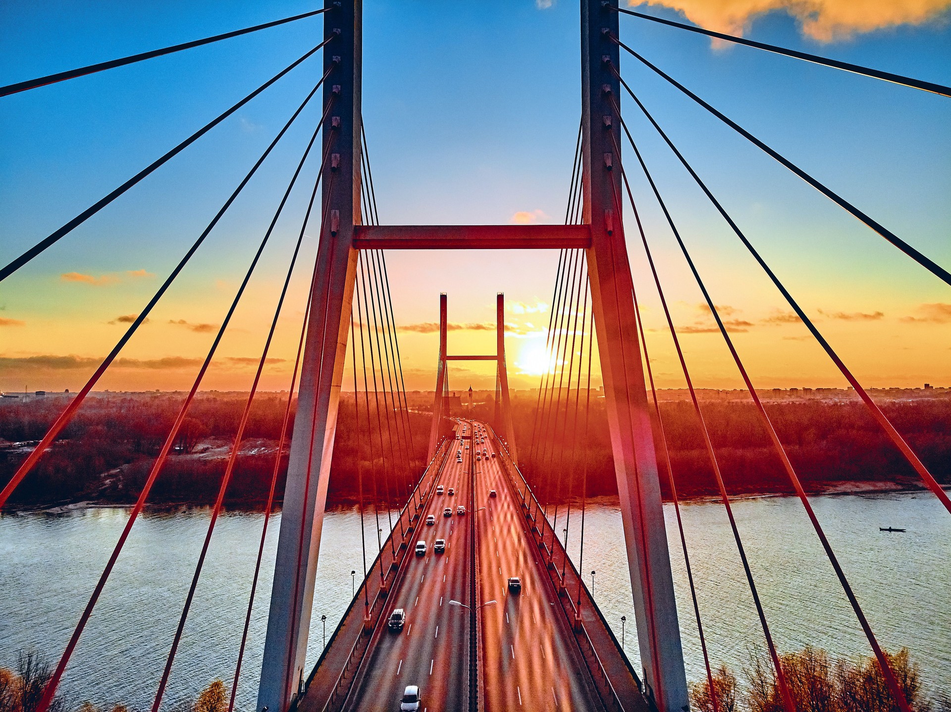Beautiful panoramic aerial drone view to cable-stayed Siekierkowski Bridge over the Vistula river and Warsaw City skyscrapers, Poland in gold red autumn colors in November evening at sunset